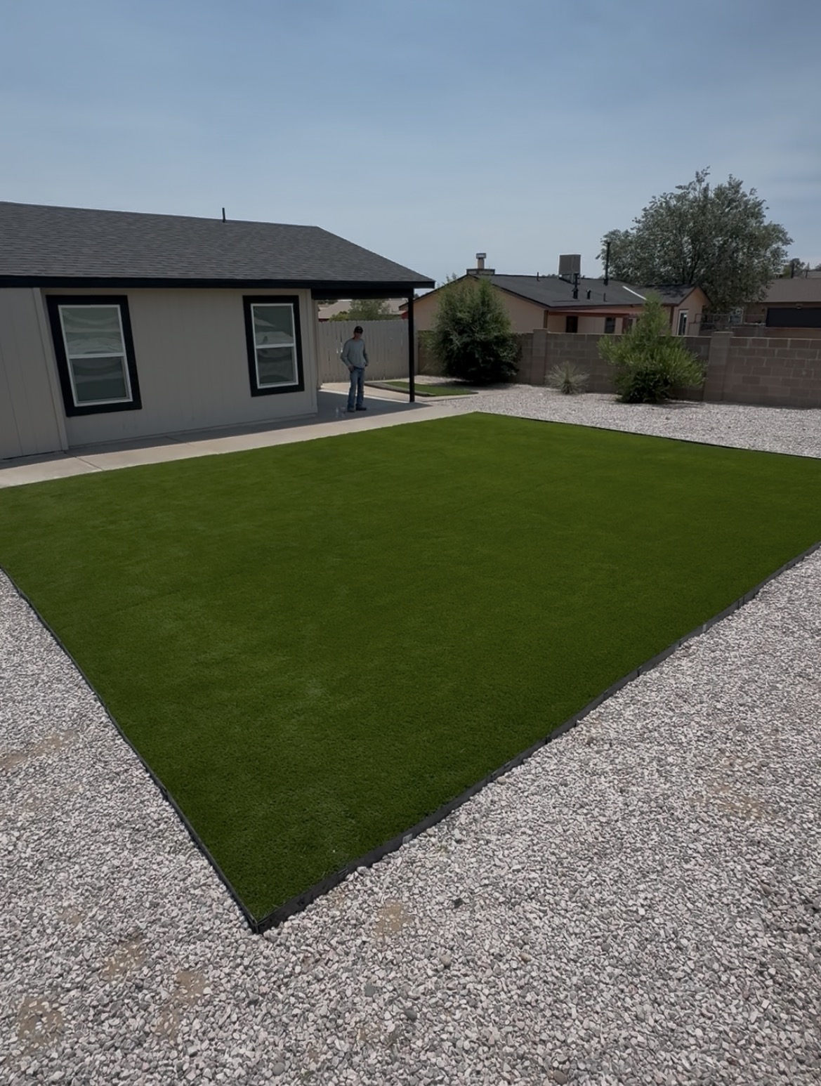 Freshly installed artificial turf lawn bordered by gravel