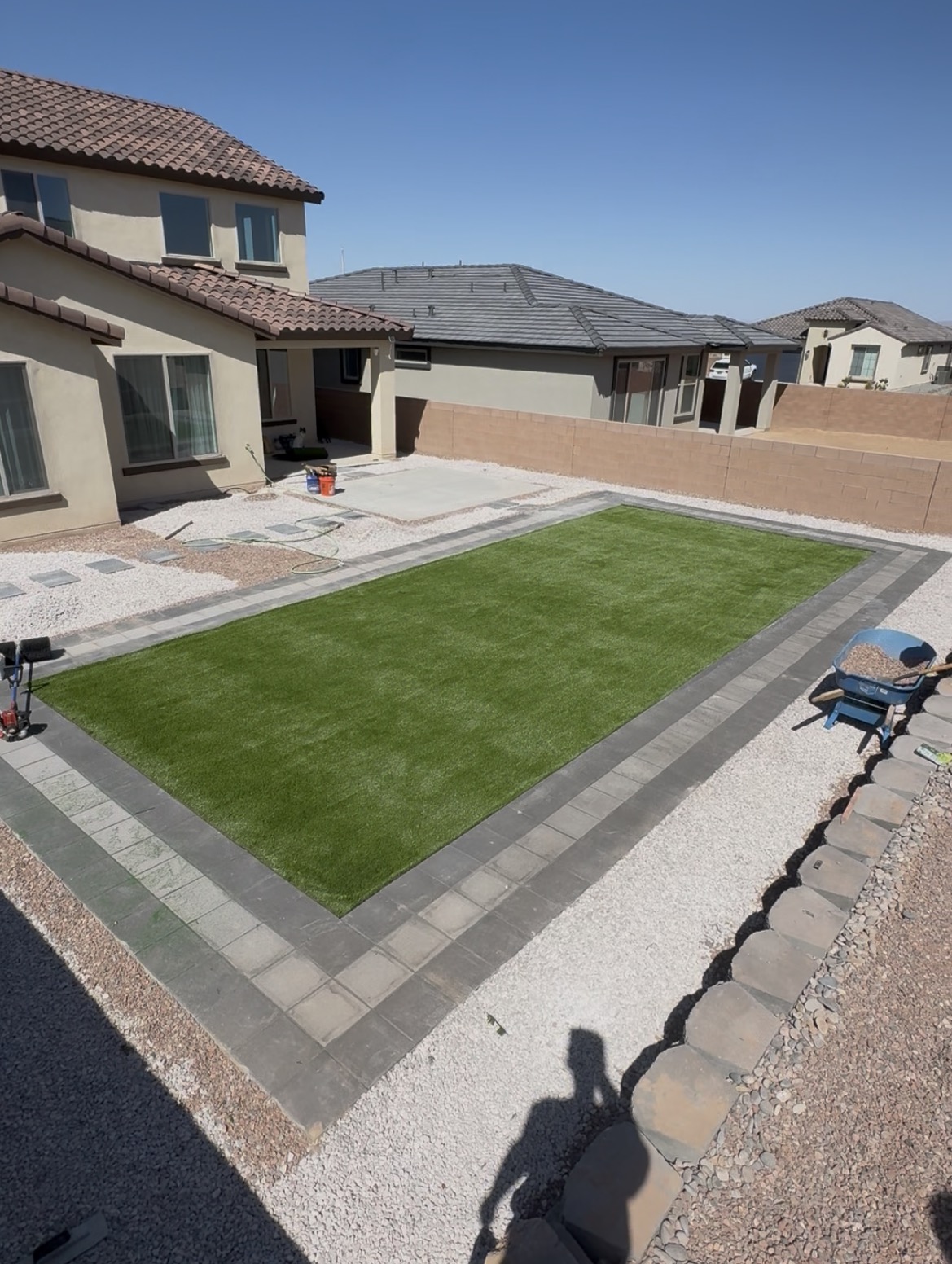 Backyard artificial turf lawn with paver border and gravel landscaping